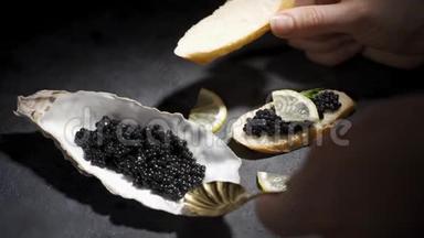 女人在面包上涂上黑色鱼子酱。 黑底牡蛎壳中的鱼子酱
